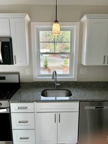 a kitchen with granite countertop a sink white cabinets and a large window