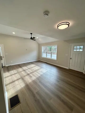 an empty room with wooden floor and windows