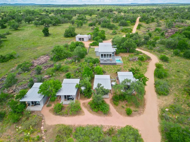 an aerial view of residential houses with outdoor space and trees