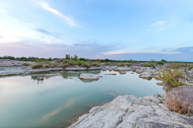 a living room with a bed a couch and dresser next to a window
