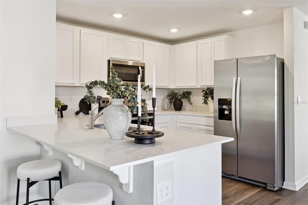 3419 Nettle Loop Tavares, FL 32778 - Photo 12 of 29 a kitchen with a refrigerator a stove and a wooden cabinets