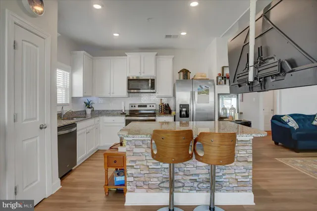 a kitchen with stainless steel appliances granite countertop a stove top oven a sink dishwasher and a refrigerator with wooden floor