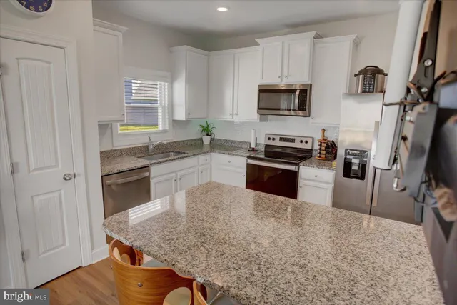 a kitchen with granite countertop a stove a sink a dining table and chairs with wooden floor