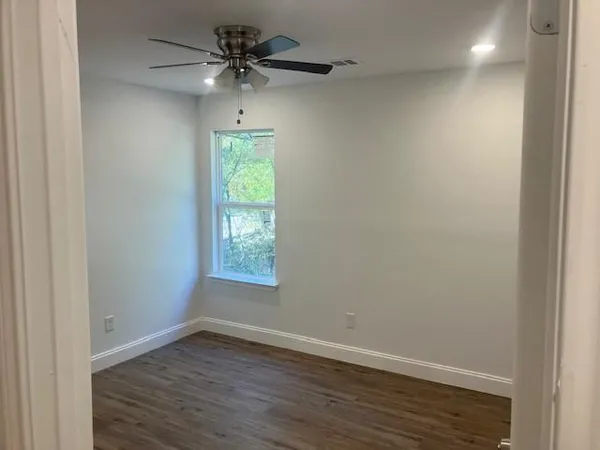 an empty room with a window and a ceiling fan