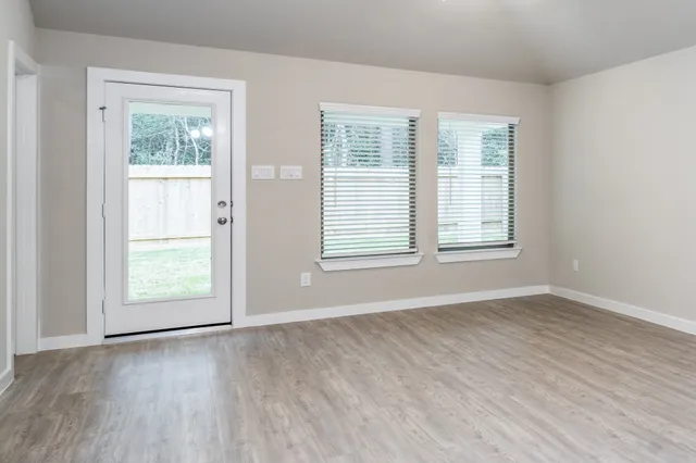 an empty room with wooden floor and windows