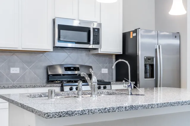 a kitchen with stainless steel appliances granite countertop a sink a microwave and refrigerator