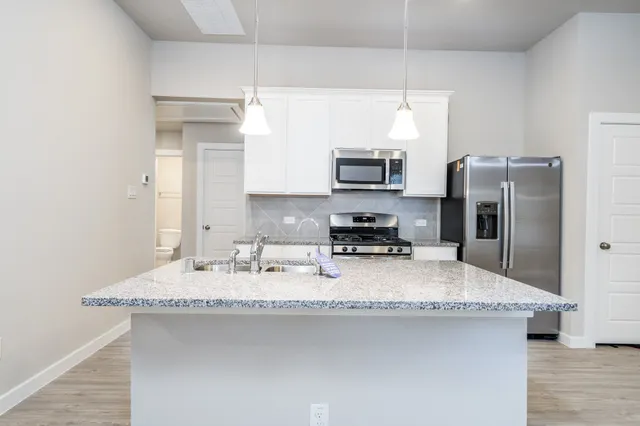 a kitchen with stainless steel appliances granite countertop a sink a stove a refrigerator a center island and cabinets