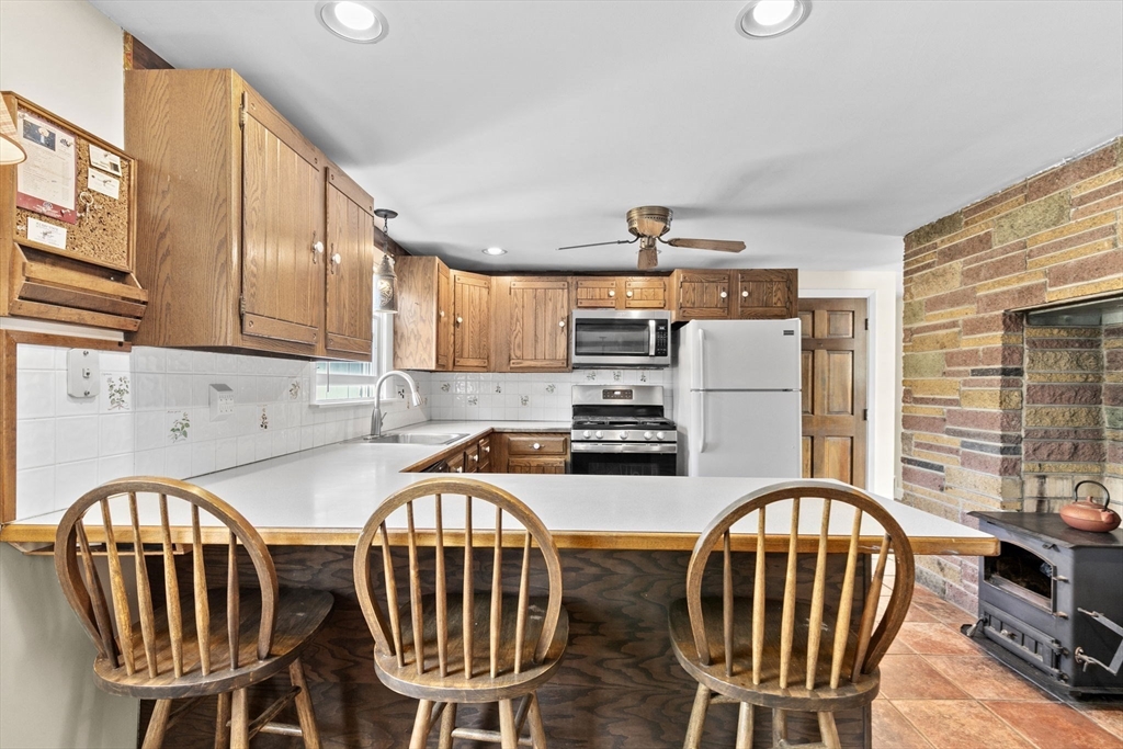 107 Tilden Road Scituate, MA 02066 - Photo 12 of 38 a kitchen with stainless steel appliances a table chairs and a refrigerator
