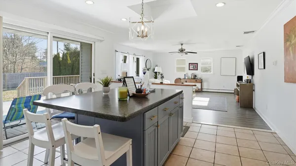 a view of a dining room and livingroom with furniture wooden floor a rug a flat screen tv a potted plant and a chandelier