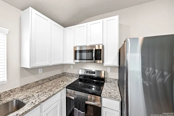 a kitchen with stainless steel appliances granite countertop a refrigerator and a stove