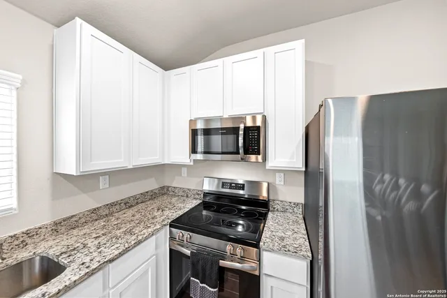 a kitchen with stainless steel appliances granite countertop a refrigerator and a stove