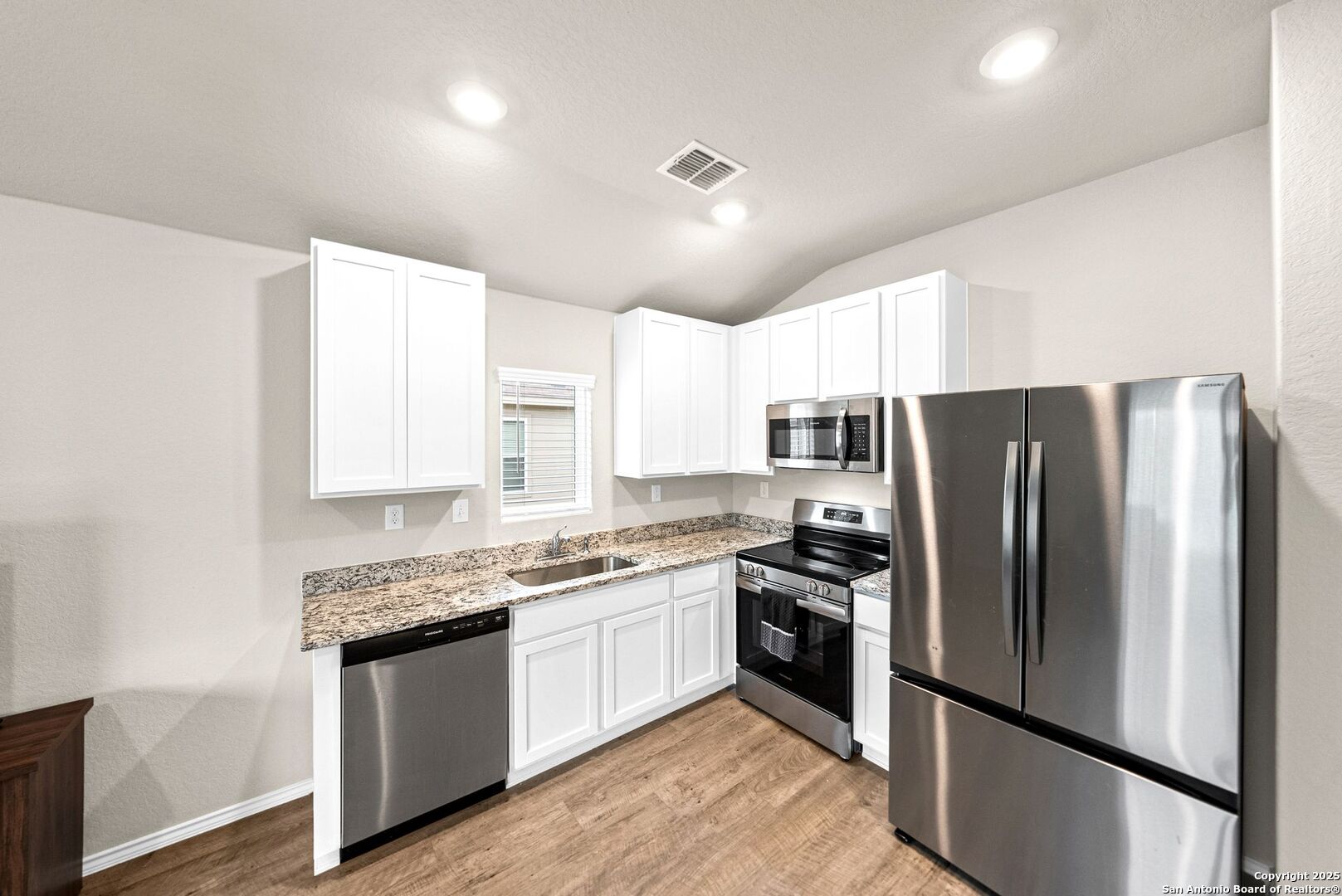 19911 Wyatt Earp Way Lytle, TX 78052 - Photo 9 of 26 a kitchen with stainless steel appliances granite countertop a refrigerator a sink dishwasher a stove and white cabinets with wooden floor