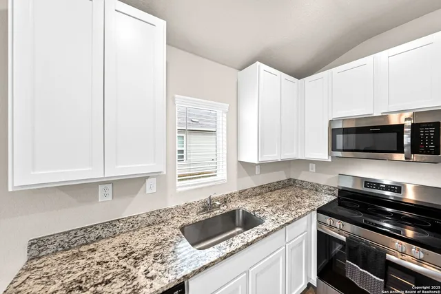 a kitchen with granite countertop a sink and a stove