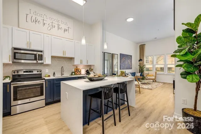 a kitchen with stainless steel appliances kitchen island granite countertop a stove a sink a refrigerator and a dining table with wooden floor