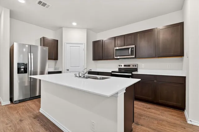 a kitchen with granite countertop a stove top oven a sink a counter space and cabinets