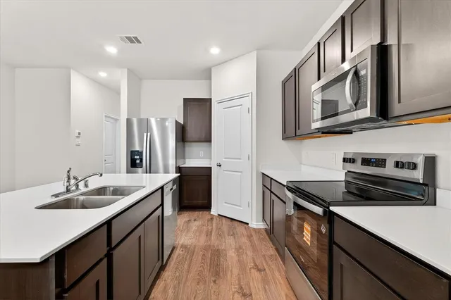 a kitchen with stainless steel appliances a refrigerator stove top oven and sink