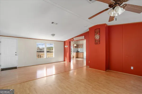 an empty room with wooden floor fan and windows