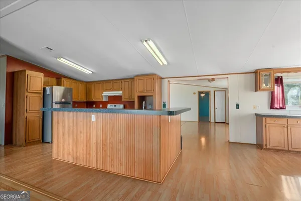 a view of a kitchen with wooden floor and a refrigerator
