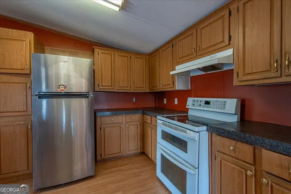 a kitchen with stainless steel appliances granite countertop a refrigerator a stove and a sink
