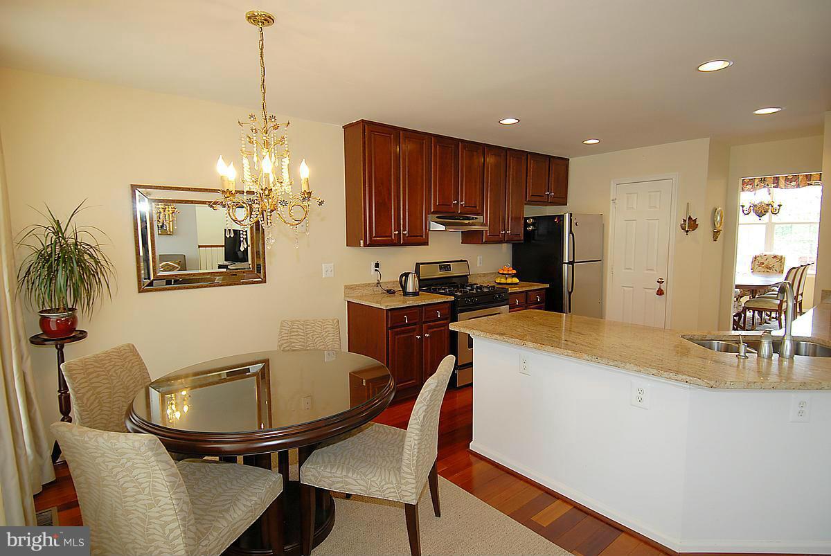 44047 Rising Sun Terrace Ashburn, VA 20147 - Photo 5 of 30 a kitchen with stainless steel appliances kitchen island granite countertop a sink a stove a kitchen island with chairs and cabinets