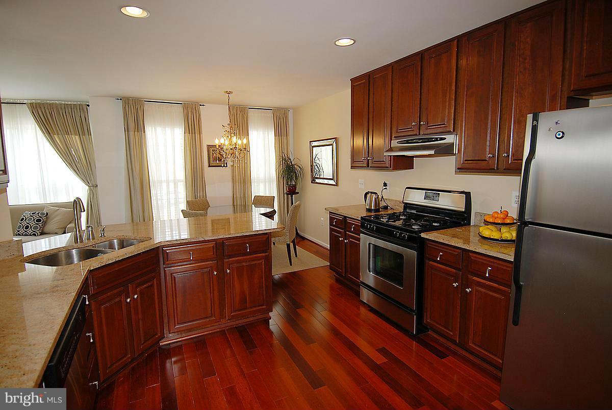 44047 Rising Sun Terrace Ashburn, VA 20147 - Photo 7 of 30 a kitchen with wooden floors wooden cabinets and stainless steel appliances