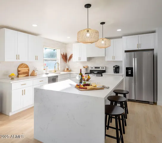 a kitchen with stainless steel appliances kitchen island granite countertop a sink a stove a refrigerator and island with wooden floor