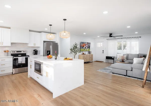 a large white kitchen with cabinets a counter and chairs