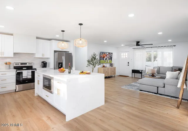 a large white kitchen with cabinets a counter and chairs