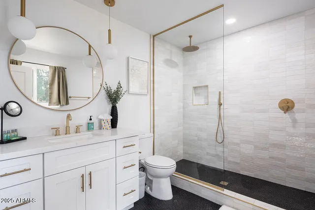 a bathroom with a double vanity sink toilet mirror and shower