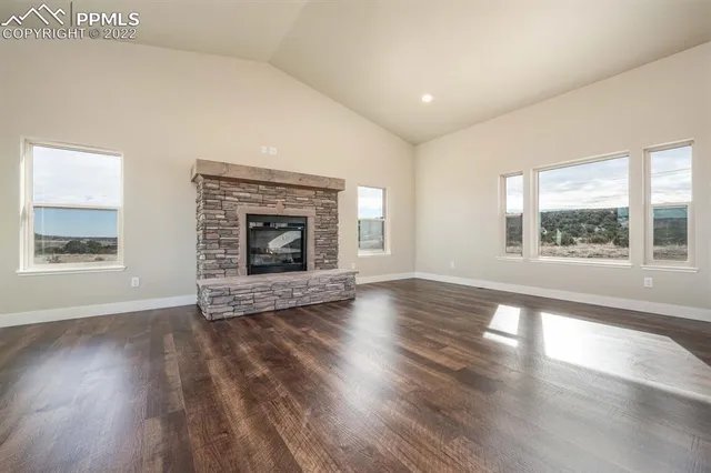 an empty room with wooden floor fireplace and windows