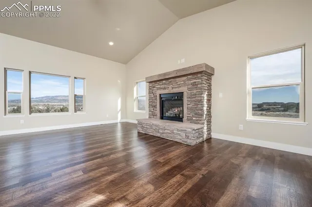 an empty room with wooden floor fireplace and windows