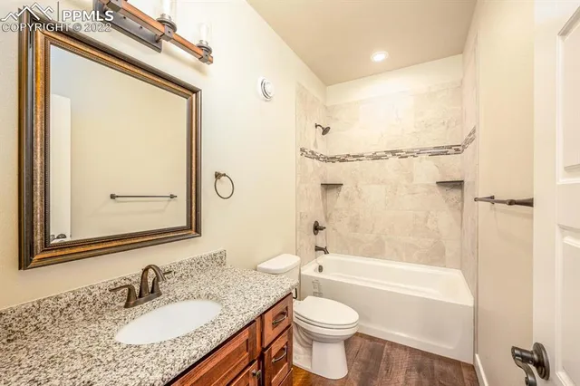 a bathroom with a granite countertop toilet sink and mirror