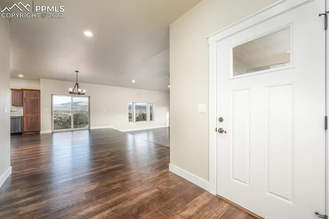 an empty room with wooden floor and a kitchen