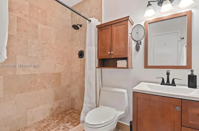 a bathroom with a toilet a sink a mirror a shower and vanity