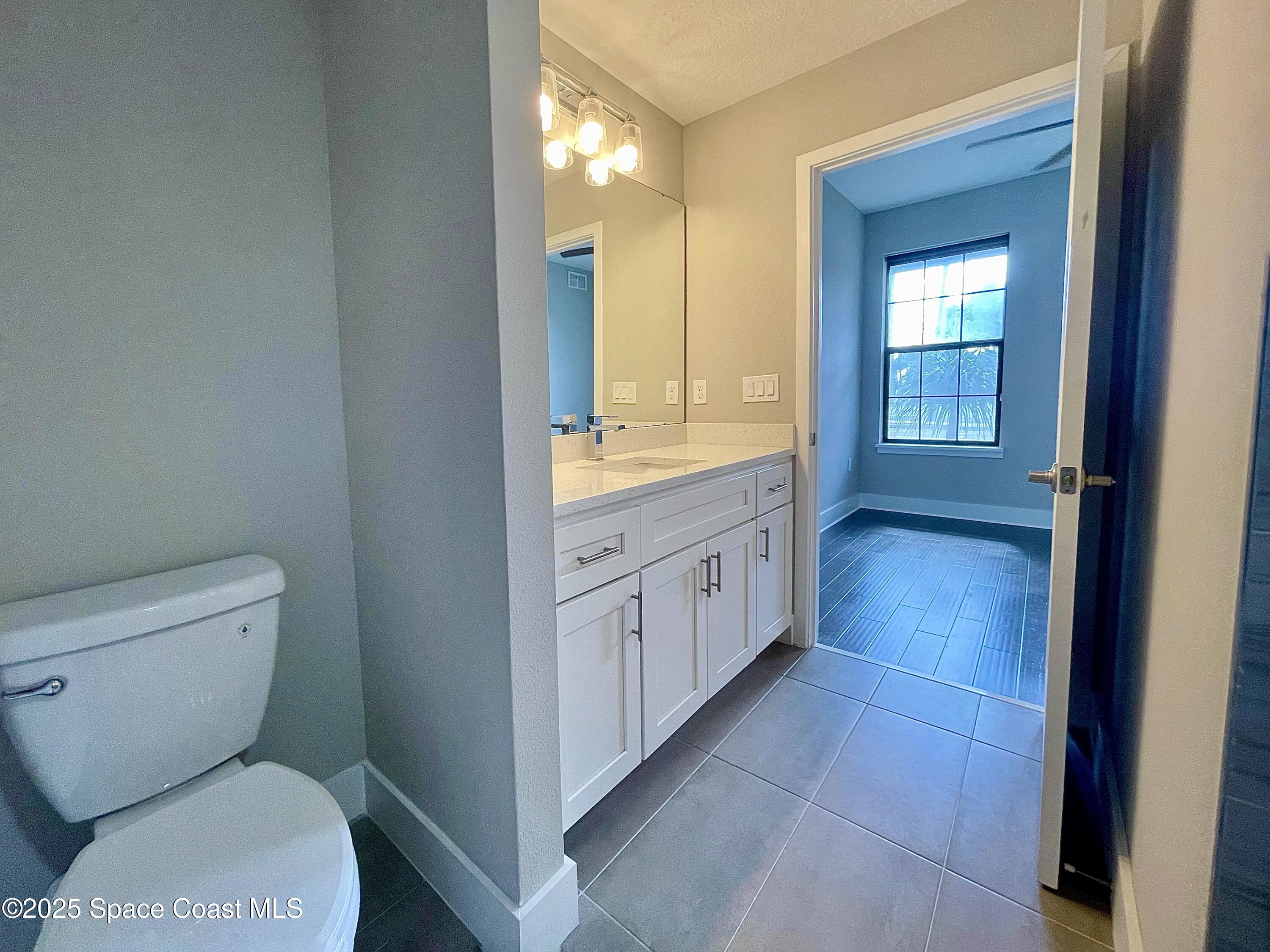 890 Florida Avenue Cocoa, FL 32922 - Photo 21 of 63 a bathroom with a granite countertop toilet a sink and a mirror