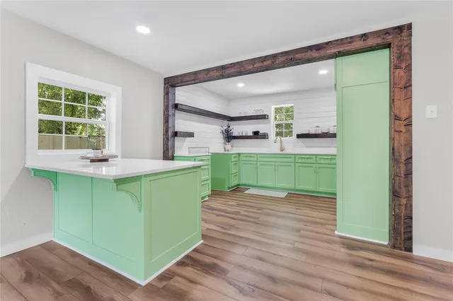a kitchen with green walls and a wooden floors