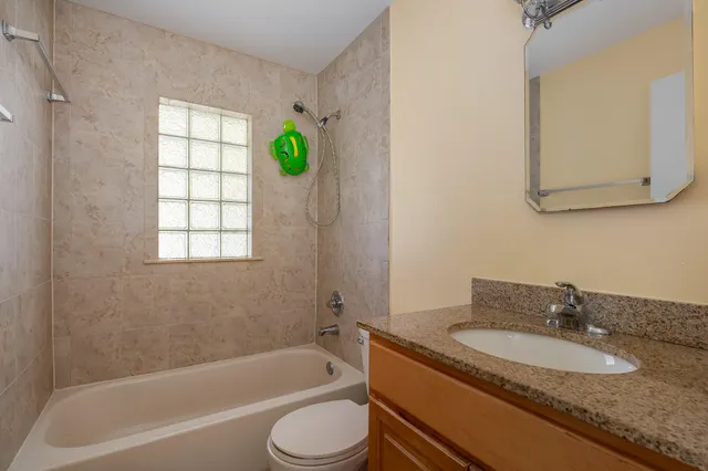 a bathroom with a granite countertop sink mirror toilet and bathtub