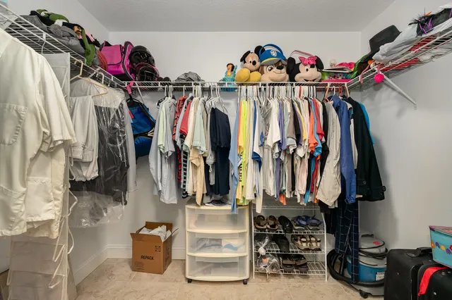 a view of walk in closet with clothes and shoes