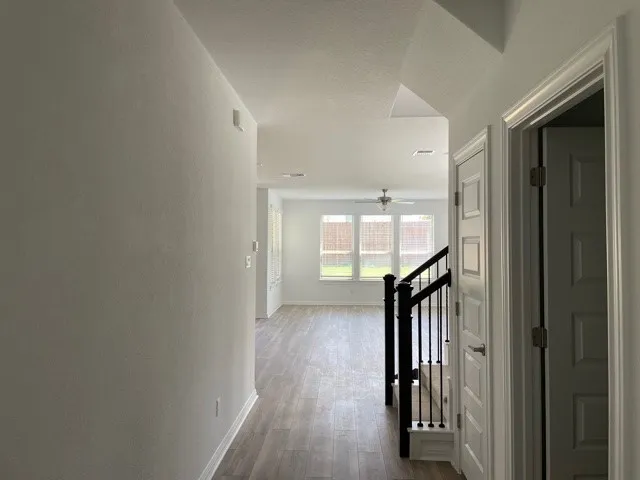 a view of a hallway with wooden floor and stairs