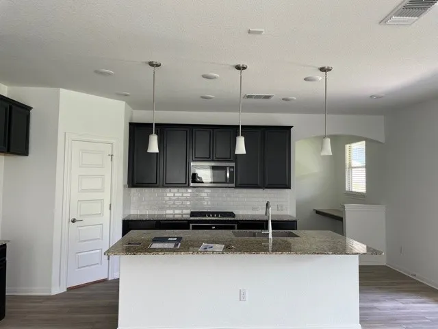 a kitchen with stainless steel appliances granite countertop a sink a stove and a refrigerator