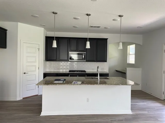 a kitchen with kitchen island stainless steel appliances a sink cabinets and a wooden floor