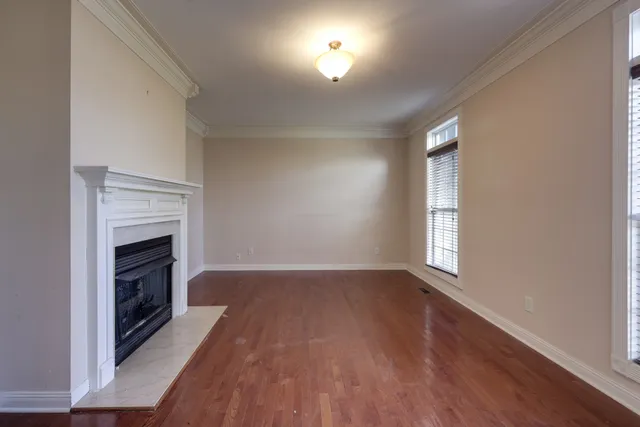 an empty room with wooden floor fireplace and windows