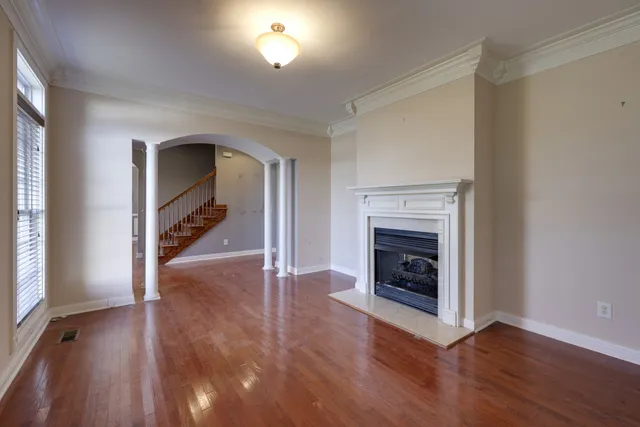 an empty room with wooden floor fireplace and windows