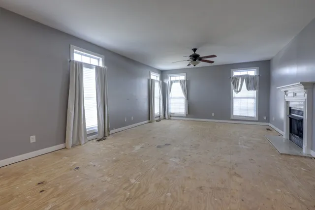 an empty room with windows and chandelier fan