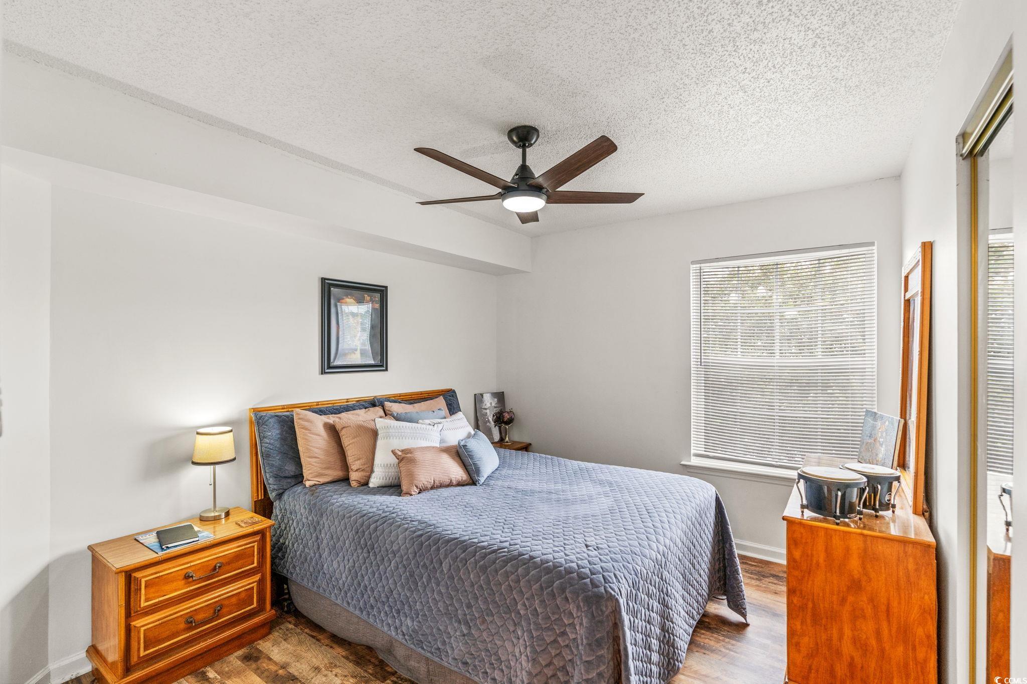 8862 Duckview Drive, Unit E Surfside Beach, SC 29575 - Photo 10 of 16 Bedroom with a textured ceiling, a closet, wood finished floors, and a ceiling fan
