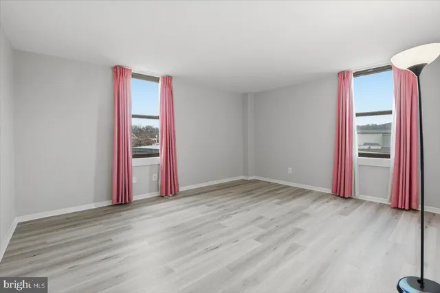 a view of a hallway with wooden floor and a mirror