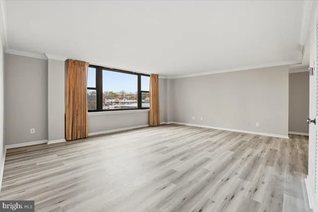 a view of an empty room with a window and wooden floor