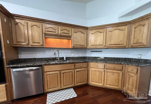 a kitchen with granite countertop wooden cabinets stainless steel appliances and a sink