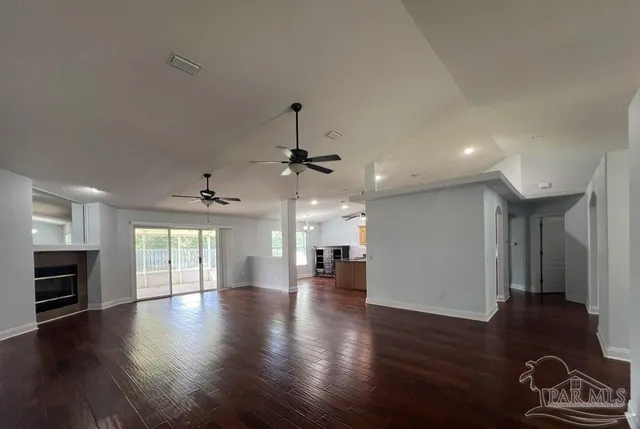 an empty room with wooden floor fireplace and windows