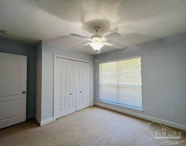 an empty room with windows and fan